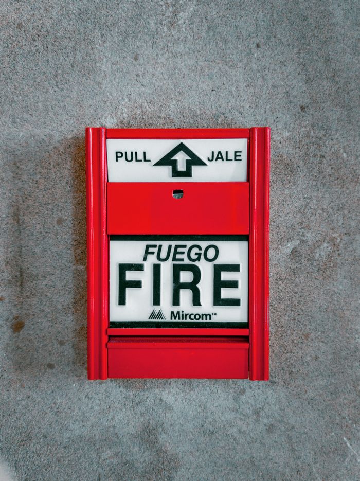 Home Red fire alarm system with text 'FUEGO FIRE'. Promotes safety and protection.