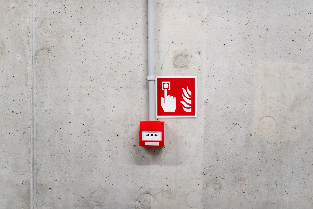 Home Red emergency fire alarm on a gray concrete wall in Poznań, enhancing safety awareness.