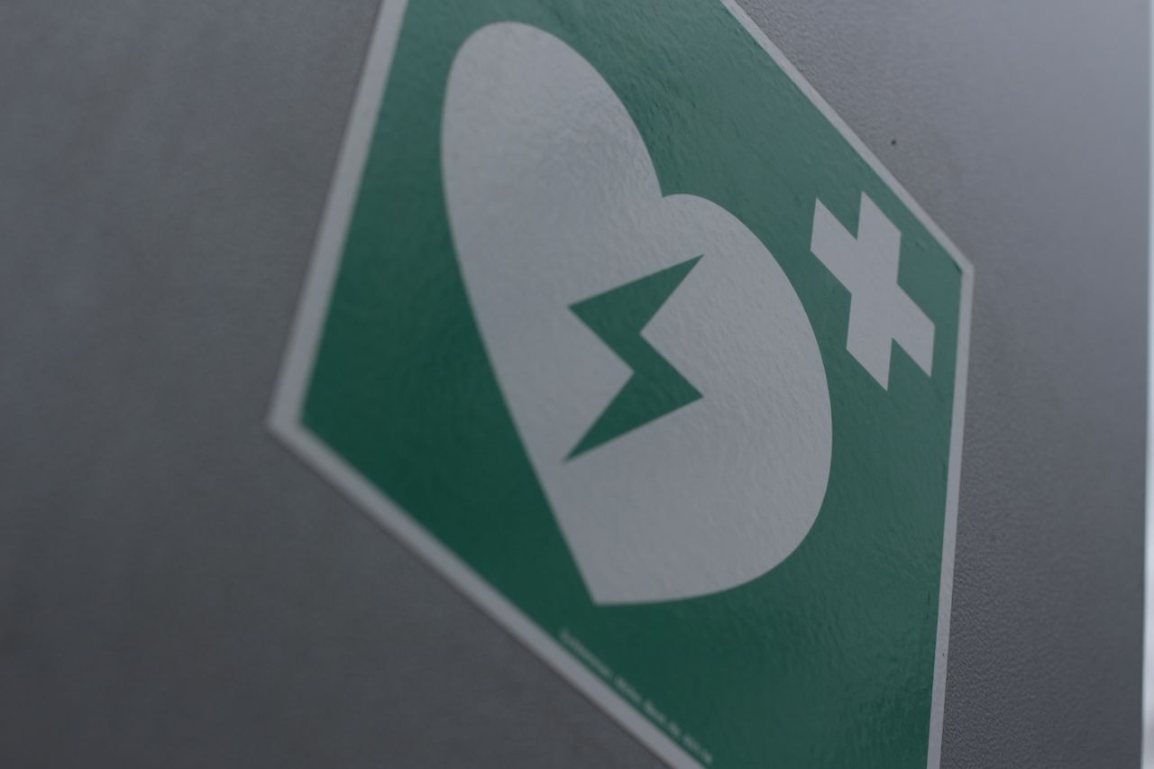 About Green first aid sign featuring a broken heart and cross symbol for medical emergency awareness.