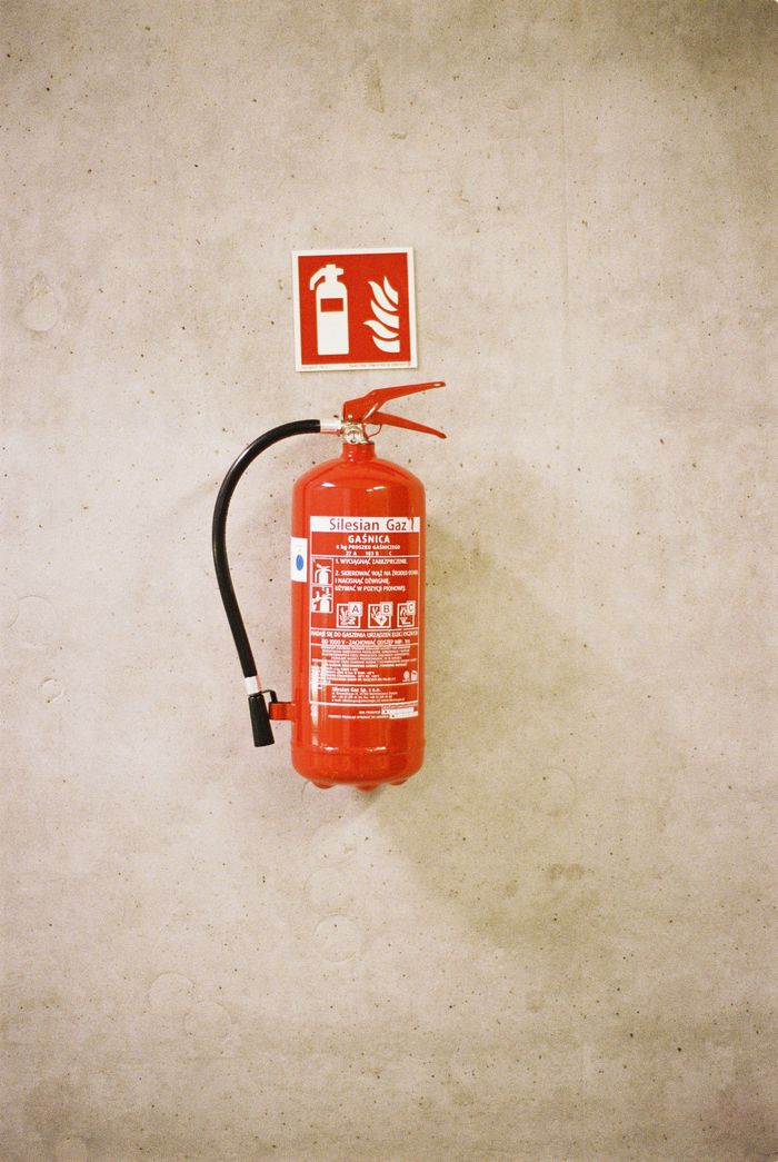 Home A red fire extinguisher mounted on a concrete wall with safety signage.