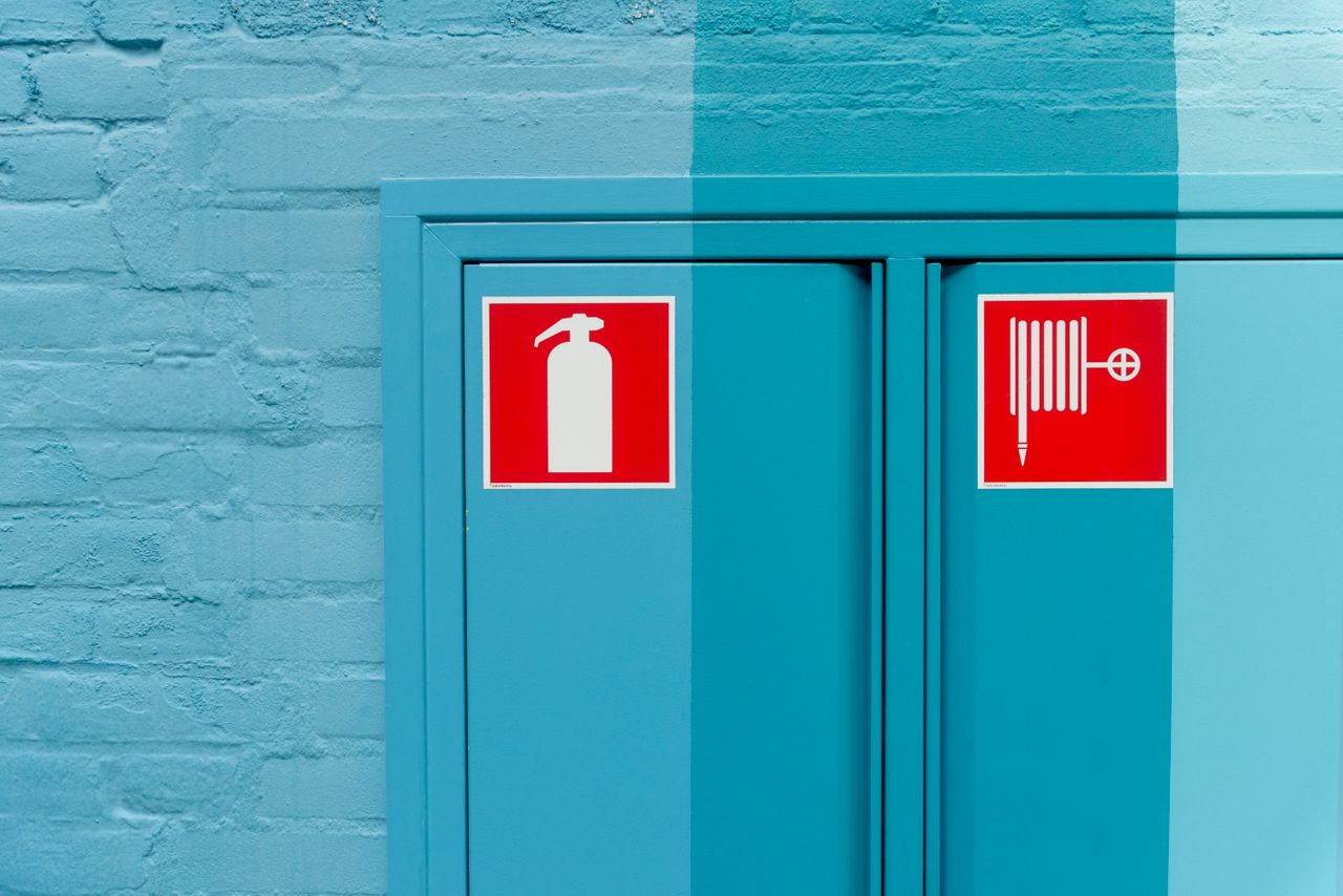 Home Blue wall featuring prominent fire extinguisher and hose signs for safety.